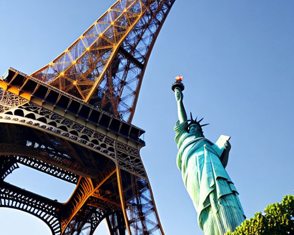 Iconic landmarks under clear blue sky: Eiffel Tower and Statue of Liberty replica.
