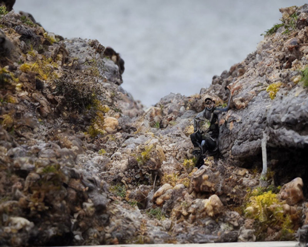 Miniature hiker figure in rocky terrain with river backdrop
