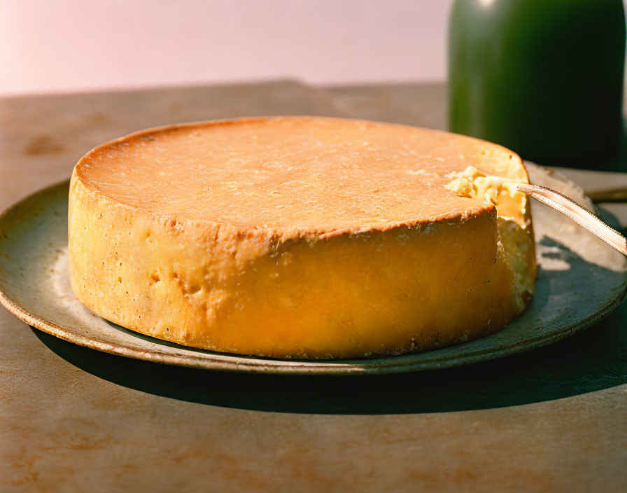 Round Cheese on Plate with Cheese Knife and Textured Rind