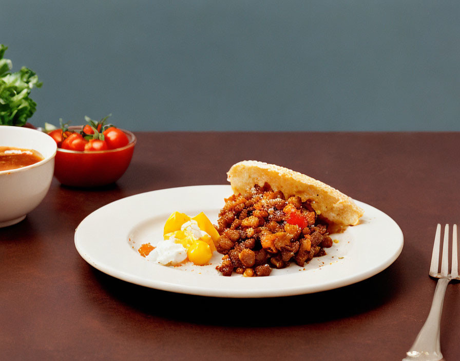 Plate of stewed beans, minced meat, bread, poached egg, sauce, and cherry tomatoes