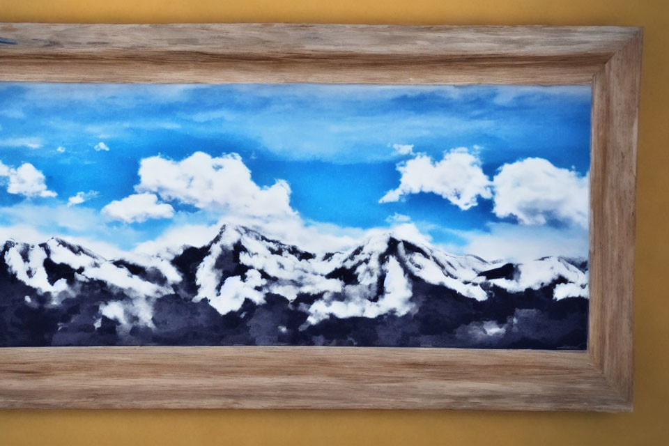 Snow-capped mountains under blue sky and clouds in wooden frame on yellow background