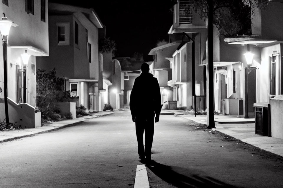 Lonely figure on dimly lit suburban street at night