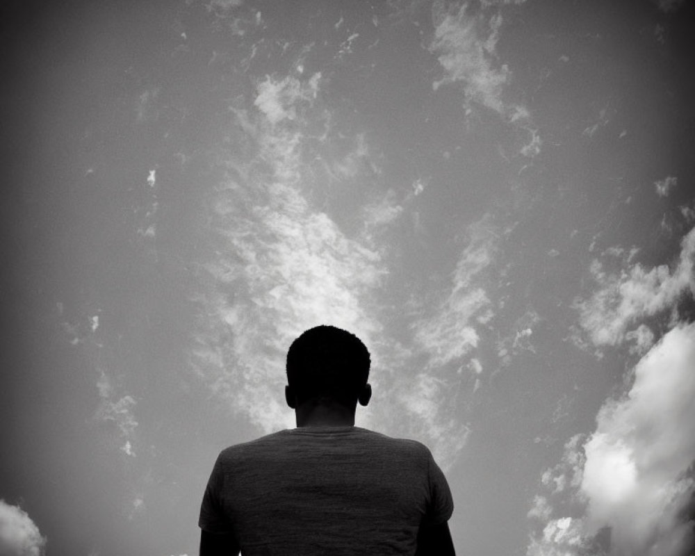 Monochrome photo of person gazing at dramatic cloudy sky