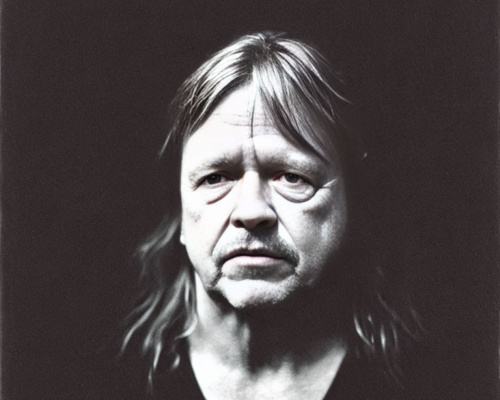 Monochrome portrait of middle-aged man with long hair and serious expression