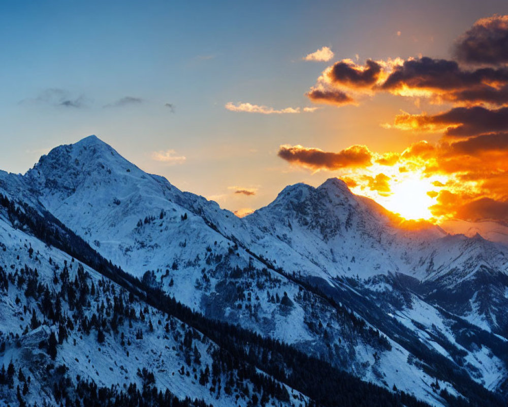 Snow-capped mountain peaks under vibrant orange and blue sunset skies
