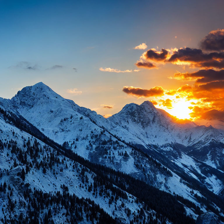 Snow-capped mountain peaks under vibrant orange and blue sunset skies