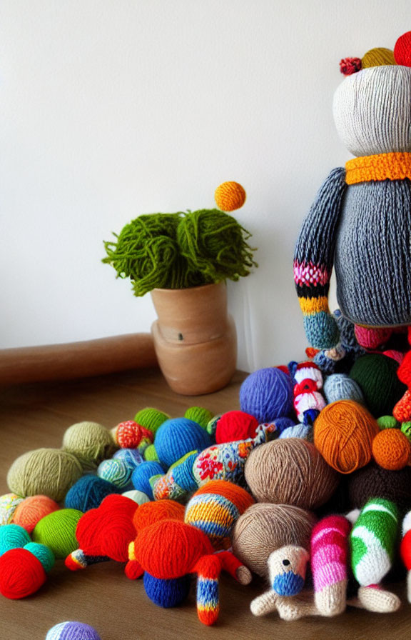 Vibrant yarn balls and knitted toys on table with plant pot
