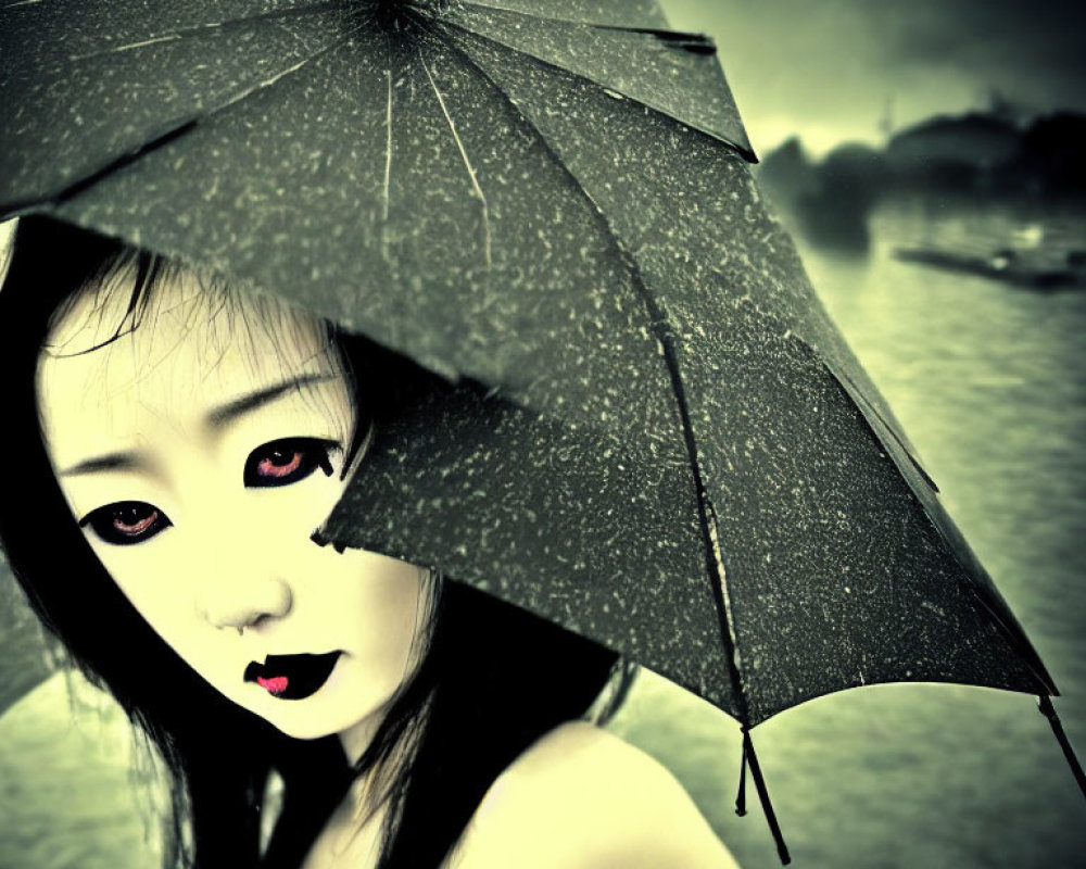 Stylized image of person with pale skin and dark makeup holding black umbrella against moody green-ton