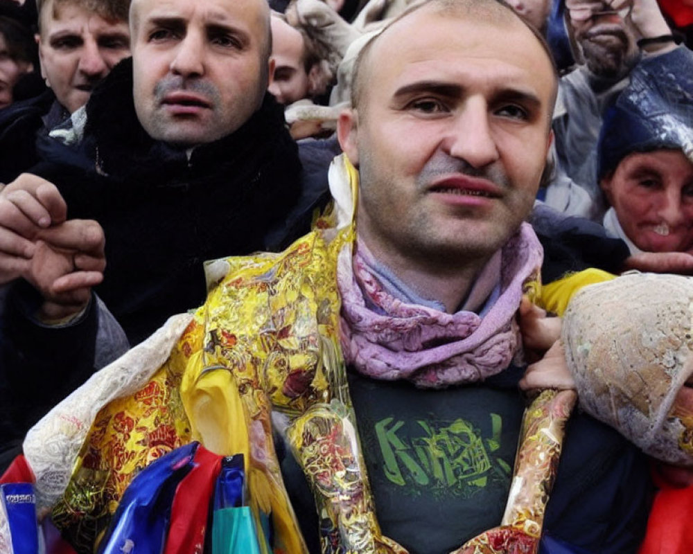 Crowded scene with bald man in scarf and ribbons smiling at camera