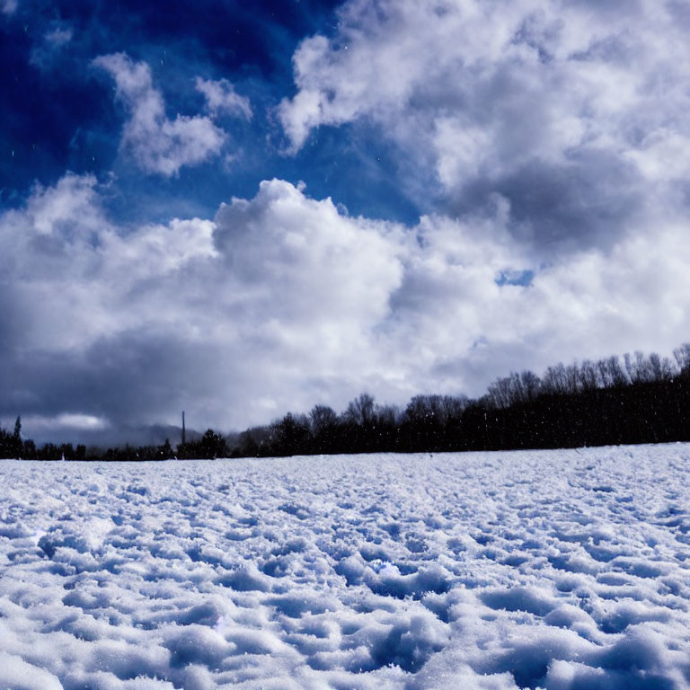 Snowy Landscape Under Dramatic Blue Sky with Fluffy Clouds