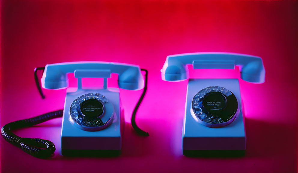 Vintage Rotary Telephones with Blue and Pink Lighting on Red Background