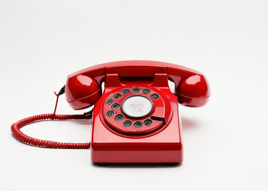 Vintage red rotary dial telephone on white background