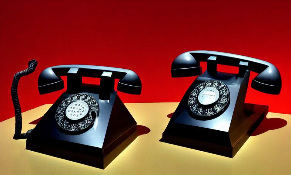 Vintage Black Rotary Telephones on Yellow Surface Against Red Background