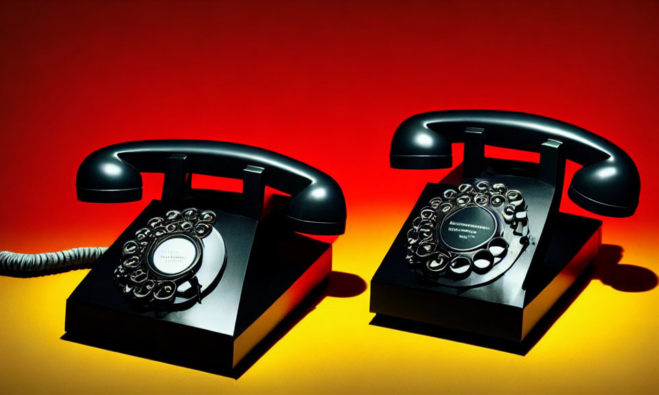 Vintage rotary dial telephones on red to yellow gradient background