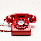 Vintage red rotary dial telephone on white background