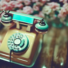 Vintage Rotary Telephone with Teal Handset on Pink Roses Background