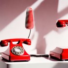 Vintage red rotary telephones with receivers off hooks on white background
