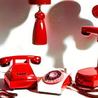 Vintage red telephones and lamp casting shadows on white surface