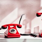 Vintage Red Rotary Telephone with Handset Off Hook on Light Background