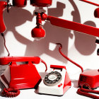 Vintage red rotary phones with disconnected handsets and tangled cords on white background