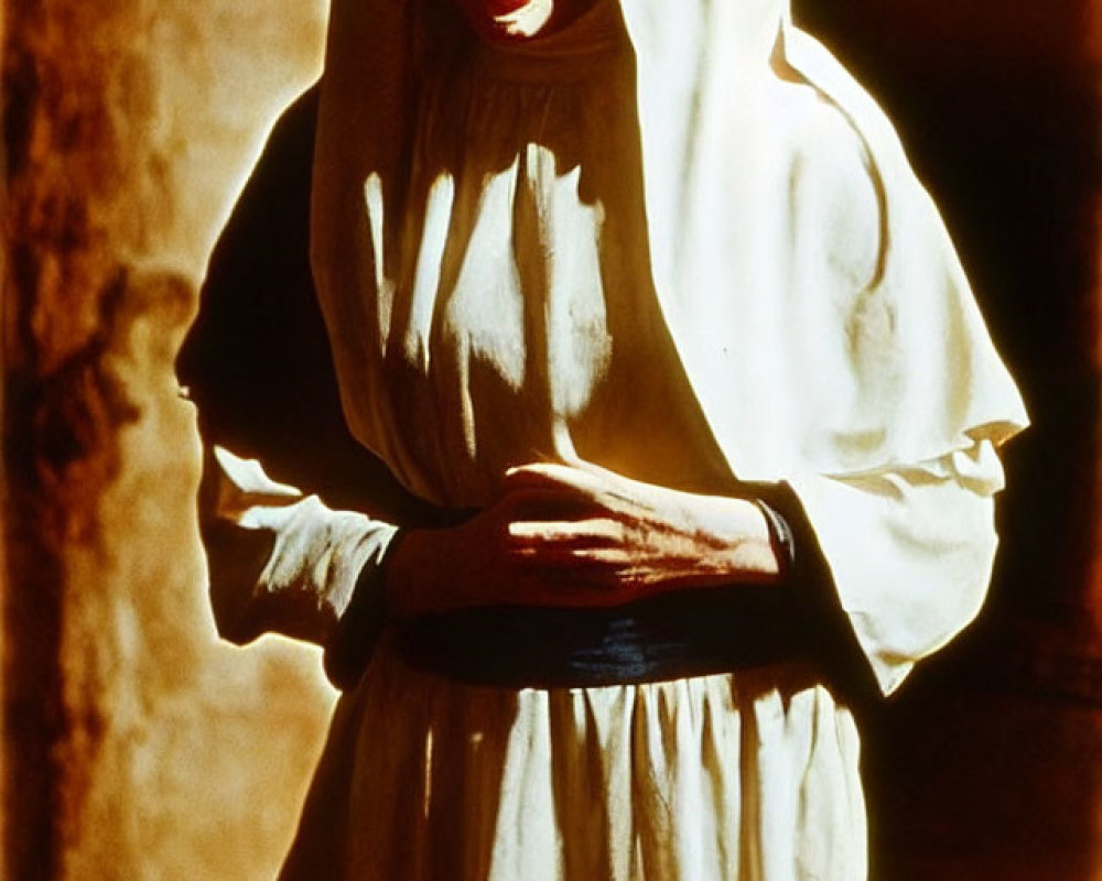 Person in White Robes with Hood in Warm Light, Expressing Concern
