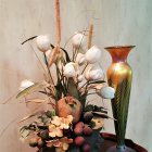 Delicate pink and white flowers with lit candle in vase against muted background