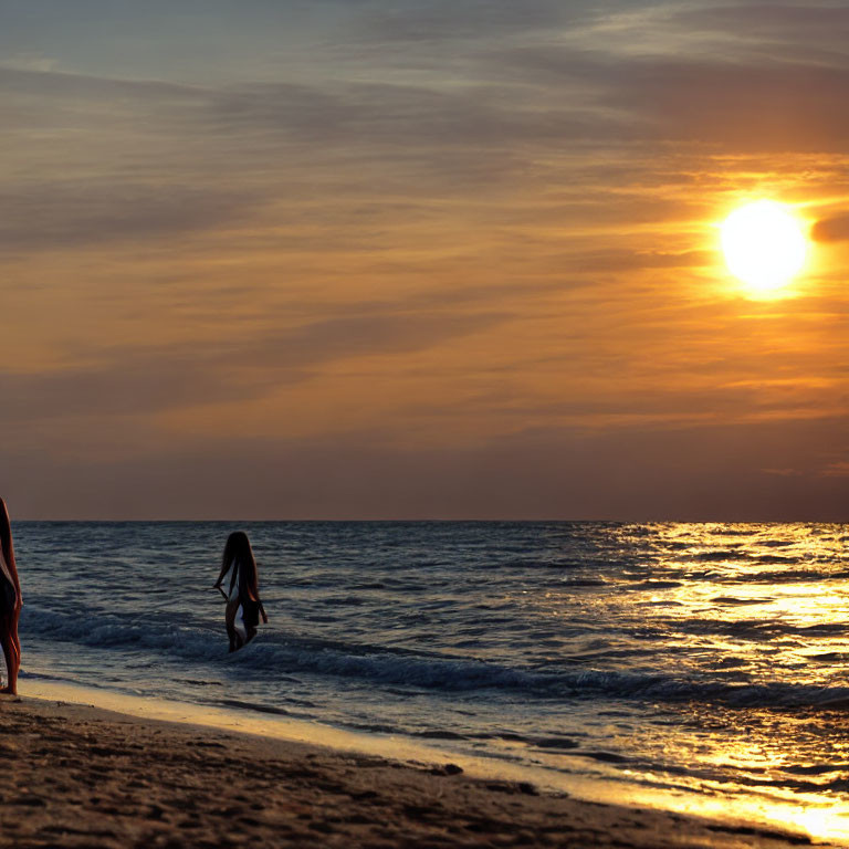 Person walking along shore at sunset with sun reflecting on ocean waves.
