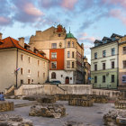 Pastel-colored European buildings around cobblestone square fountain
