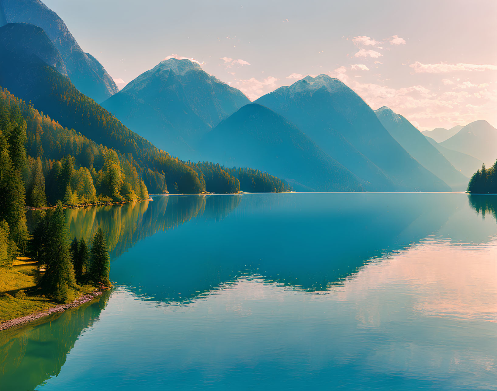 Serene lake with reflections of green trees and mountains under golden sky