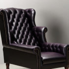 High-Back Armchair with Deep Purple Leather Upholstery and Ornate Wooden Legs