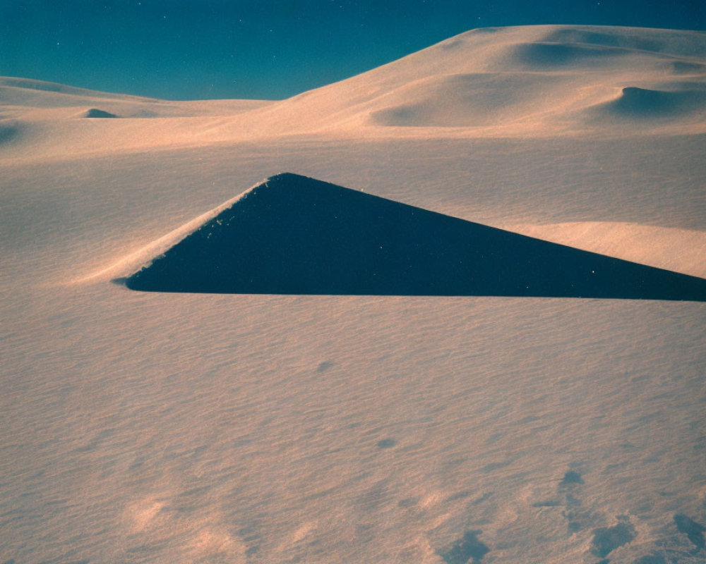 Snowy Landscape with Dark Triangular Shape in Soft Blue Sky