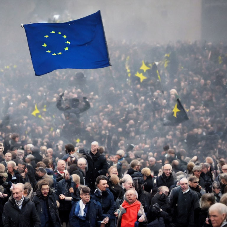 European Union flag waves over crowded gathering with hazy atmosphere