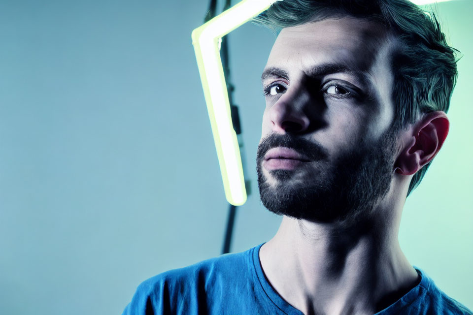Bearded man in cool-toned light with neon background