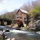 Scenic watermill by stream with flowers and bridge