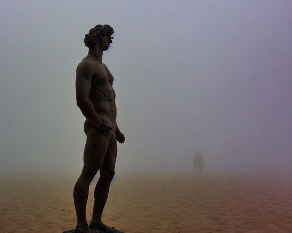 Muscular male figure statue on misty day with person walking away