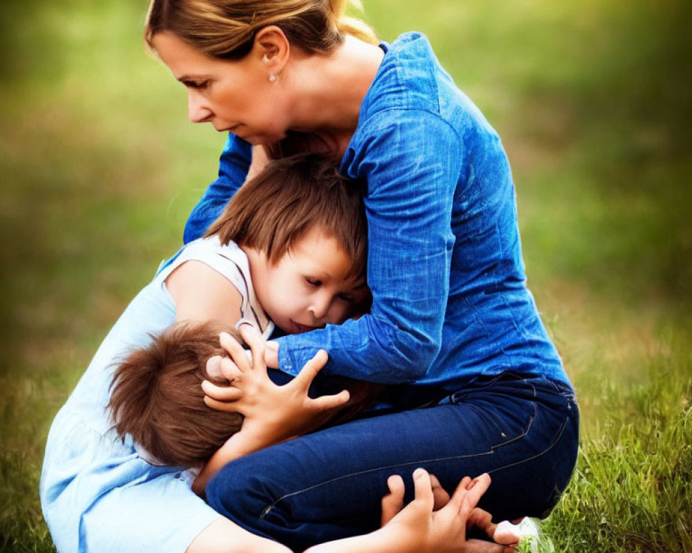 Woman in Blue Shirt Embracing Two Children on Grass