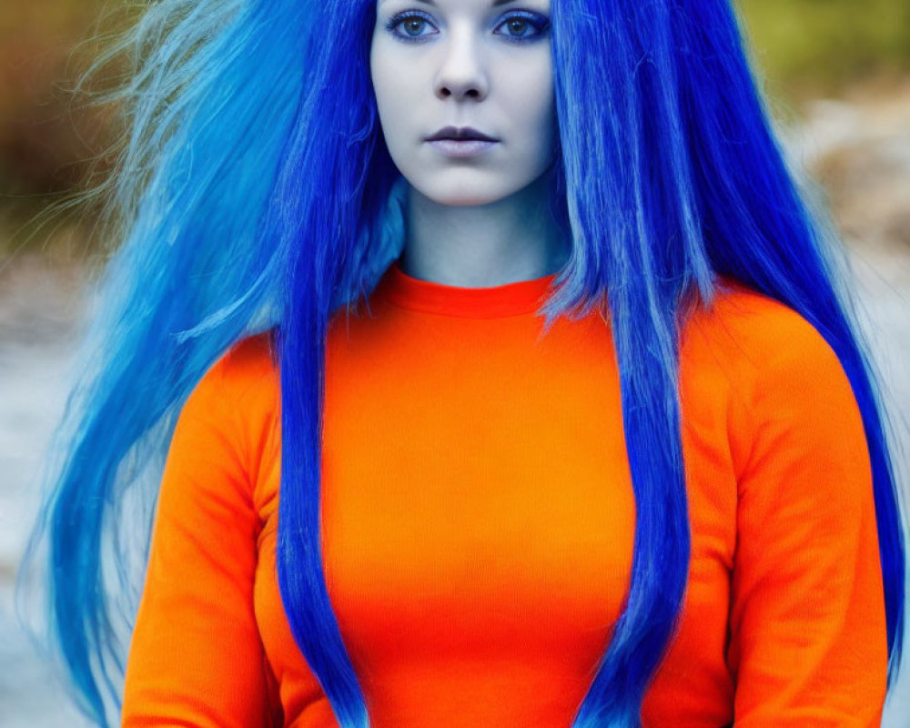 Vibrant blue-haired woman in orange top with intense gaze outdoors
