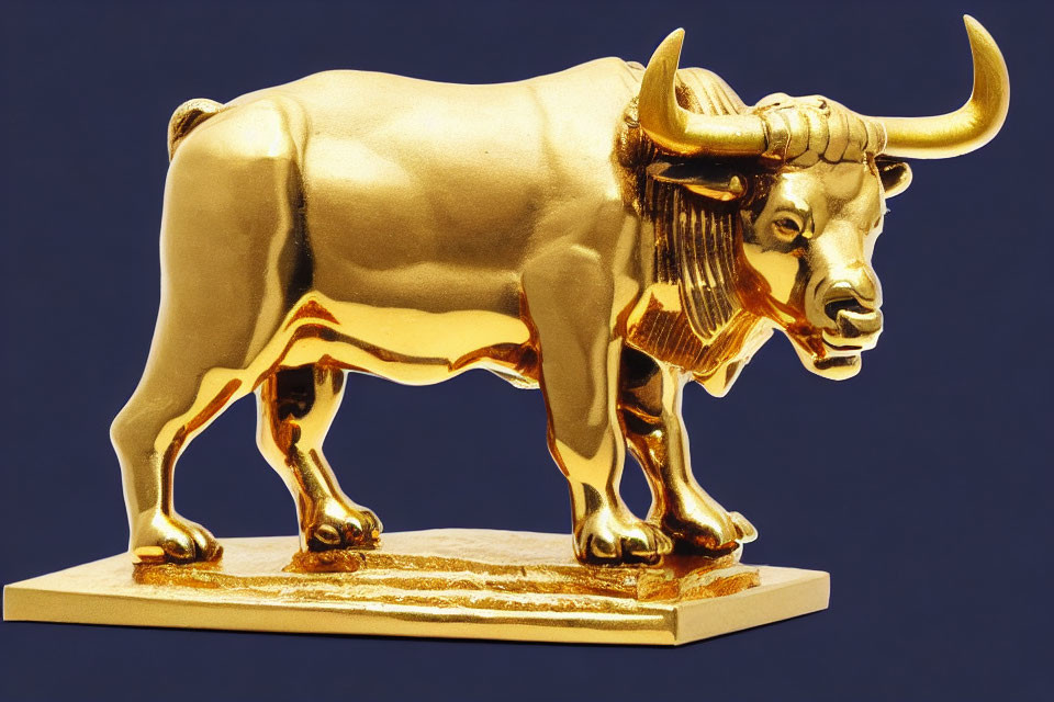 Shiny gold bull statue with horns and muscles on blue background