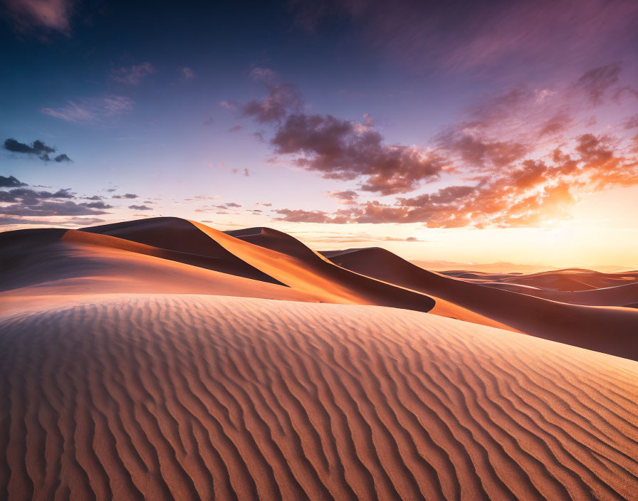 Scenic sunset over rippling sand dunes in pastel sky