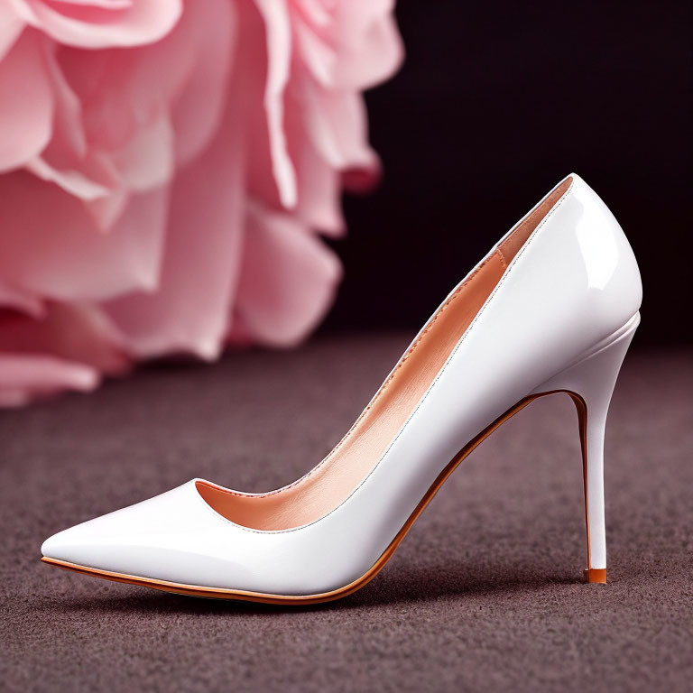 White high-heeled stiletto shoe on soft pink backdrop with floral design