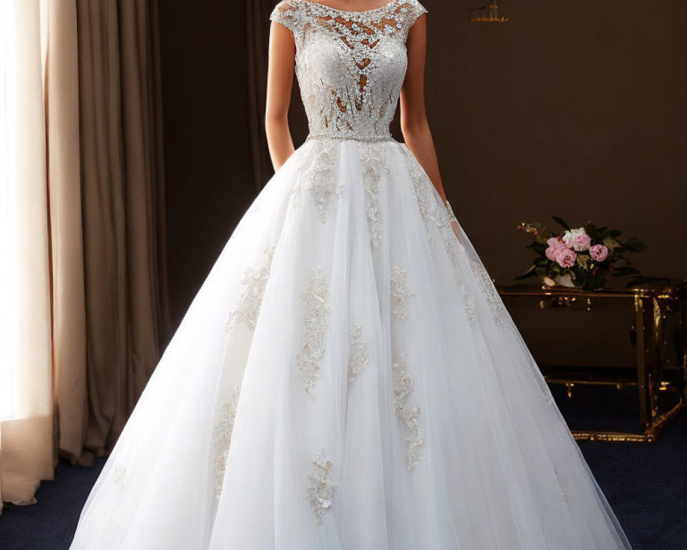 Elegant white wedding dress with intricate lace detailing and sheer overlay in softly lit room