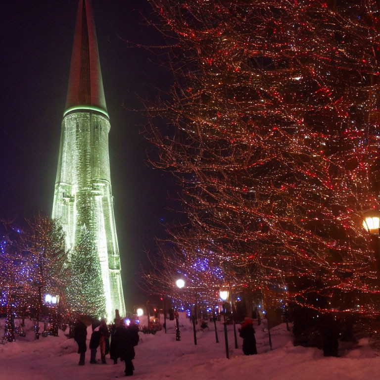 Snowy Night Scene: People, Red-Lit Trees, Green Tower