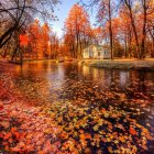 Tranquil autumn landscape with waterfall, stream, colorful trees, leaves, and cabin