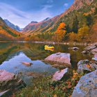 Tranquil autumn scenery with colorful foliage, reflective lake, and majestic mountains.