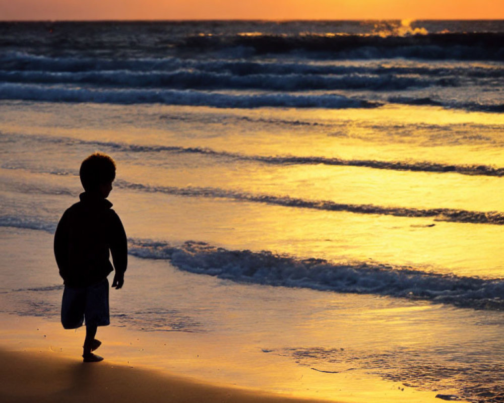 Child Silhouetted on Sandy Beach at Sunset