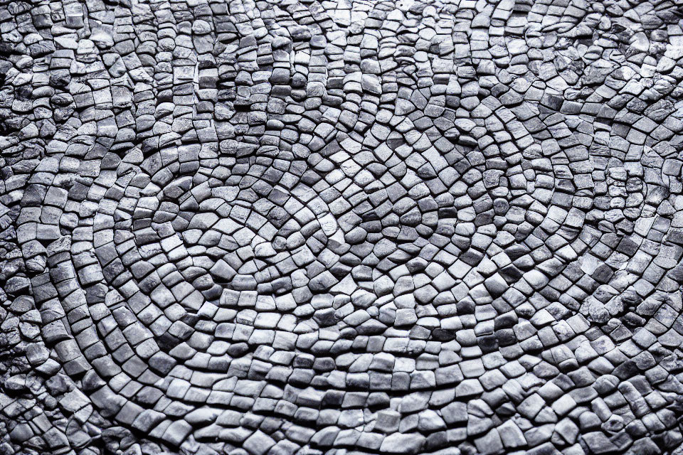Detailed close-up of circular cobblestone pavement texture in varying shades of gray