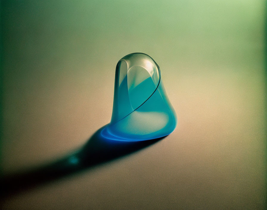 Transparent Glass Droplet Casting Blue Shadow on Gradient Green-and-Tan Surface