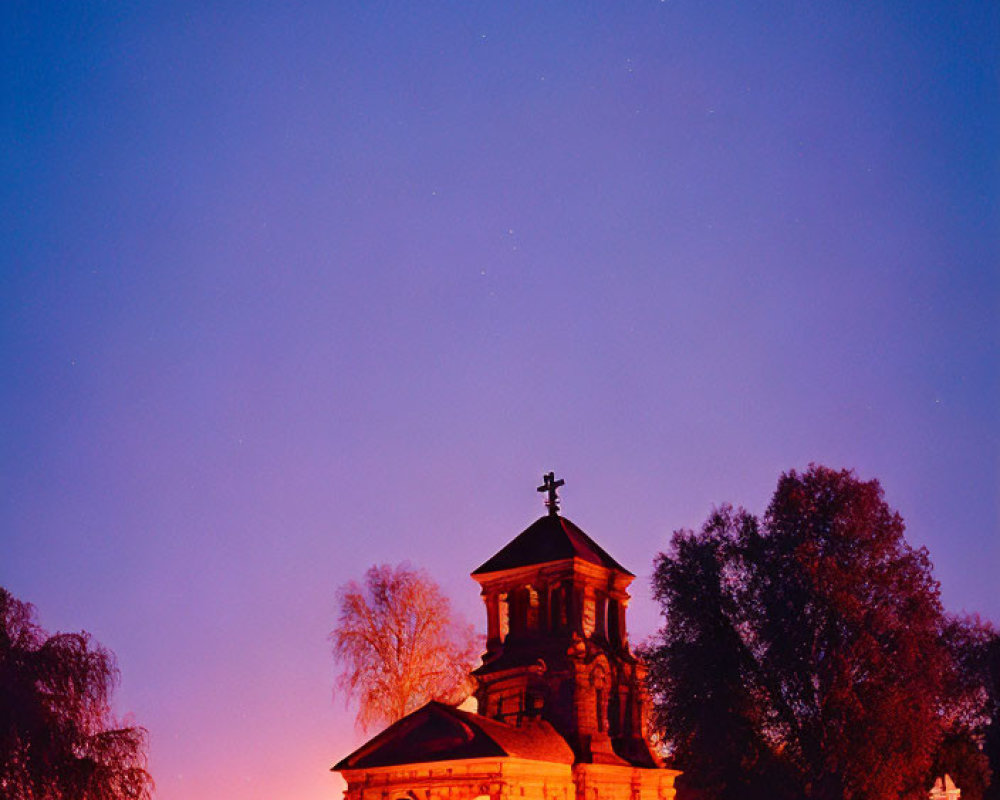 Church with cross on dome under twilight sky with stars and colorful horizon.