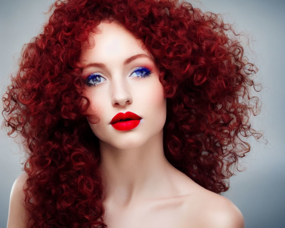 Voluminous red curly hair, blue eyeshadow, and red lipstick on woman portrait