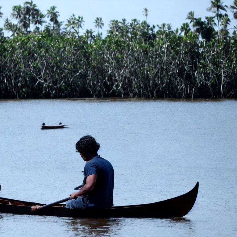 Canoe paddling on calm river, mangrove trees backdrop, second canoe afar